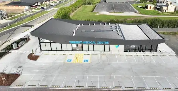 Aerial view of Trident Medical Centre, a modern single-storey clinic with glass storefront and a large parking lot including accessible spaces.